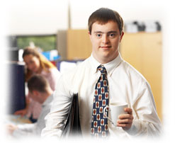 Photograph of a man with Down's Syndrome in business dress holding a cup of coffee in an office setting