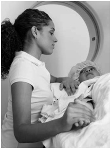 A mother holds the hand of her young child when he is set up to receive a CT scan.