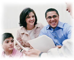 Photograph of a man looking over paperwork with a smiling couple and their son.