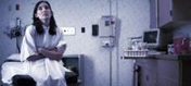 Fotografía de una paciente vestida con una bata y sentada en un cuarto de exámen del hospital