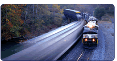 Two trains passing around bend in fall landscape.