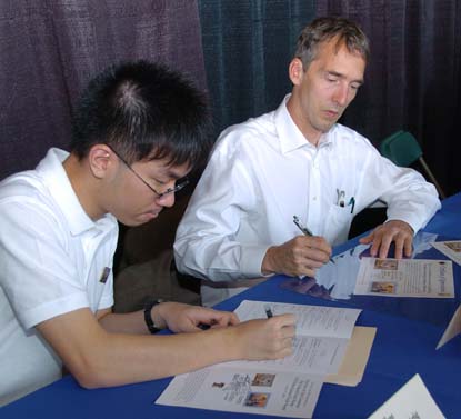 Federal Duck Stamp artist Joe Hautman and Junior Duck Stamp artist Seokkyun Hong signing stamps, First Day of Sale Programs and certificates. Photo by  Lavonda Walton/USFWS   