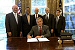 President George W. Bush signs an Executive Order implementing his Volunteers for Prosperity initiative in the Oval Office Thursday, Sept. 25, 2003. Pictured with the President are, from left: Deputy Secretary of Commerce Samuel W. Bodman; Deputy Secretary of Health and Human Services Claude A. Allen; Administrator, Agency for International Development, Andrew Natsios; Under Secretary of State Alan Larson; and Director, USA Freedom Corps, John Bridgeland.