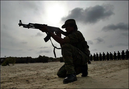 A woman fighter of the Tamil Tigers takes a shooting position in Sri Lanka, July 2007. AP Photo.