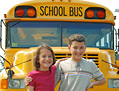 Photo of two school children with a school bus in the background.