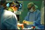 Photo thumbnail: LCDR Shirley, a Navy surgeon, and CDR Lowell, a USPHS surgeon, repair a child’s club foot.