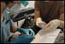 Photo thumbnail: Dentist LCDR Janice Kim (left) and an Air Force dental hygienist work together on a patient in Port-au-Prince, Haiti.