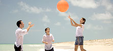 Two boys and a girl playing with a beach ball.