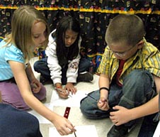 Three students talking and drawing on paper