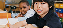 Two boys in a classroom writing