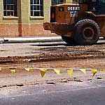 Photo of a construction vehicle near a city street covered in dirt.