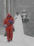A researcher loaded down with equipment trudges through the snow.