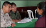 Photo Thumbnail: LT Katherine Morris, a physician assistant, consults with a patient while a U.S. Marine looks on.