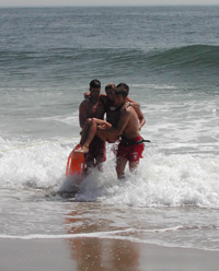 Rip current survivor, after rescue by lifeguard, being helped from ocean by two lifeguards. Mock rip current rescue demonstration by lifeguards. Rip Current Awareness Week, June 5, 2007, Gateway National Recreation Area, Sandy Hook , NJ , press conference. 