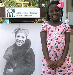 Young African American girl standing by a poster of Zora Neale Hurston