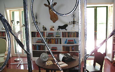 View of the Hemingway writing studio through a wrought iron railing - table with typewriter, bookshelf, mounted buck