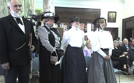 Three women and a man, dressed as the founders of the library from 1907, stylishly dressed in frock coats and hoop skirts