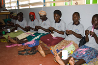 Participants in an income generating project at Reach-Out Mbuya Kinawataka Clinic create beadwork. Photo by Arne Clausen.