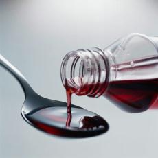Photograph of cough syrup, pouring from bottle to spoon