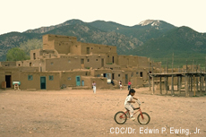 Photograh of a Native American boy riding a bicycle at Taos Pueblo, Taos, New Mexico