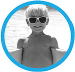 A boy wearing sunglasses holding a water float in front of a swimming pool.