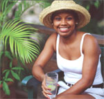 A woman sitting and smiling, enjoying a glass of water with lime.