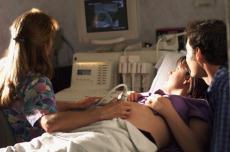 Photograph of a female technician performing an ultrasound on a pregnant woman accompanied by a man