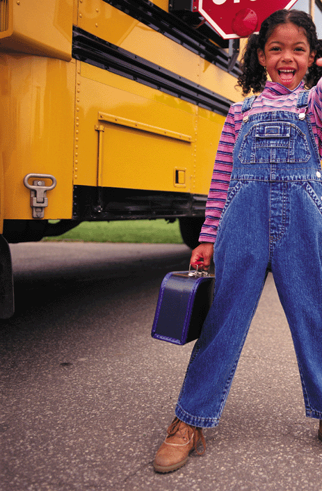 girl standing in front of a school bus