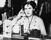 Old photo of woman with headphones on at radio crystal set.