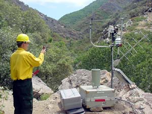 NOAA image of IMET Chuck Redman from the NOAA National Weather Service forecast office in Boise, Idaho, setting up the FireRAWS equipment near a wildfire.