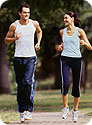 A man and woman jogging in a park.
