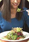 A woman eating salad.