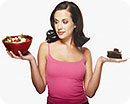 A woman holding a salad in one hand and a slice of chocolate cake in the other hand.