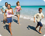 A mother, father, son and daughter running on the beach.