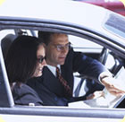 A woman with a car salesman discussing paperwork inside a car.