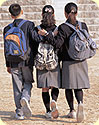 Two girls and one boy walking away; each has a backpack on.