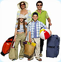 A mom, dad, son and daughter with luggage, a beach ball and a grocery bag full of food.