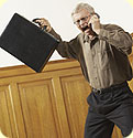 An older man holding a briefcase yelling into his cel phone.