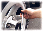 A man measuring tire pressure with a tire gauge.