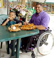 man in wheelchair with boy eating outside