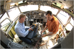 Larry Schneider (left) and Mike Dinallo use the PASD diagnostic on a cockpit wiring bundle in a retired Boeing 737 at a Sandia FAA test center.