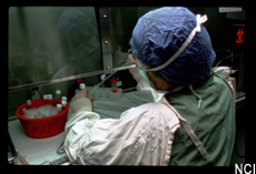 Photograph of a scientist wearing protective gear working at a lab bench