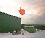An orange tethered balloon  is being launched at the Poker Flat facility