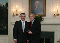 President Bush presents the President's Volunteer Service Award to Air Force spouse Bob Davison from Columbus Air Force Base, Mississippi, before the White House celebration of  Military Spouse Day on Tuesday, May 6, 2008.  Davison's wife, Major Lisa Davison, has served in the Air Force since 1996. At his wife’s current duty station, Davison started the combined Mississippi and Alabama Chapter of Operation Homefront, through which he has raised more than $350,000 in donations, including more than one million phone card minutes for distribution to service members.  Davison secured funding and donations to provide catered meals and 2,000 backpacks filled with toiletries, blankets, and clothes to injured service members and their families who were transitioning through the base or onto frontline hospitals.  Davison also volunteers with R.I.D.E.S – Ready to Improve Development, Esteem, Strength, and Spirit, which provides therapeutic horseback riding for special-needs children.  While at various other duty stations, Davison has also helped to collect 1,000 toys and raised $10,000 to support Fisher House and established an Airmen’s Food Pantry to provide short-term food aid to military families facing financial difficulties.