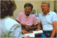 Image of elderly couple speaking with a clinician