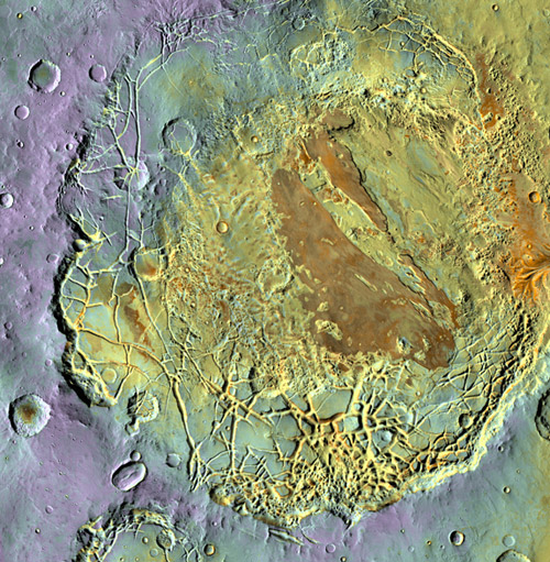 This false-color infrared image portrays a large impact crater viewed from orbit. The crater is nearly filled with sediment that is cracked into irregular, shardlike pieces inside the crater rim. In the middle is a flat-topped mesa. Both the crater sediment and the surrounding terrain are dotted with smaller impact craters.