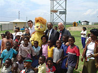 On World AIDS Day, December 1, 2006, Eric M. Bost, U.S. Ambassador to South Africa, traveled to Diepsloot in Guateng Province in South Africa to see a PlayPump in action. The innovative PlayPump water system is powered by children's play. It consists of a merry-go-round attached to a water pump and provides a sustainable and child-friendly water delivery system. Complementing the PlayPump installations are positive living messages featuring the image of Kami, the HIV-positive Muppet from Takalani Sesame.