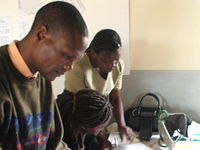 HIV Counseling and Testing Week District supervisor and National Task Force supervisor reviewing monitoring forms and data with an HIV counselor at an outreach site in rural Dowa District, Malawi