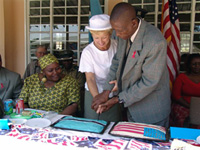 Canavan and Kgosi Molefi cut a cake in honor of Peace Corps volunteer Mary Ann Camp who was leaving after two years of service to the village. Seated is Chobe District AIDS Coordinator Botho Tangane.