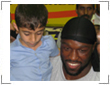 Photo of Mo Lawal holding on to a child while visiting with Iranian fans.